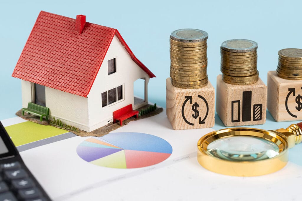 Haus, Münzen und Vergrößerungsglas auf Finanzdiagramm