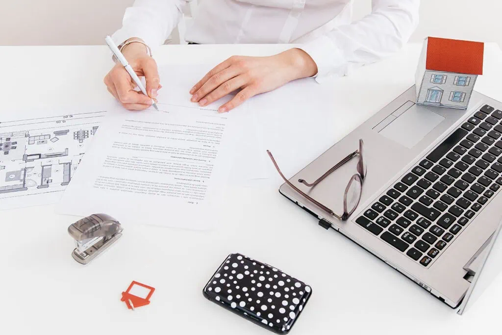 Vertragsunterschrift am Schreibtisch mit Laptop und Dokumenten.